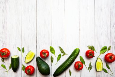 Domates, avokado, salatalık, bütün ve yarımlar, ıspanak yaprakları ve dereotu, düz beyaz ahşap bir yüzey üzerinde yatıyordu. Sağlıklı gıda konsepti. Gıda arkaplanı.