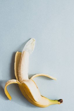 Güvenli seks yaratıcı konsept. Kullanılmış prezervatif soyulmuş bir muza konur. Mavi bir arka planda düz uzandı