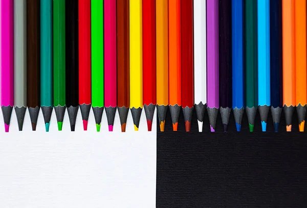 Close-up of colored pencils on a black and white background. Top view with copy space