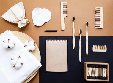 Sıfır israf yaşam tarzı konsepti. Boş defter, bambu diş fırçaları, saç fırçaları, kulak çubukları, yeniden kullanılabilir pamuk süngerler. Bej bir arkaplanda düz yatıyordu.