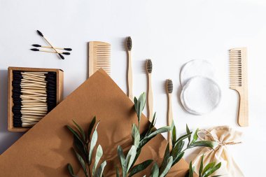 Çevre dostu yaşam tarzı konsepti. Zeytin dalı uzatılmış modern natürmort, ev için sıfır atık ürün. Bambu diş fırçaları, kulak çubukları, yeniden kullanılabilir pamuk süngerler ve ahşap taraklar..