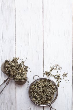 Çay süzgecinde kurutulmuş ahududu yaprakları. Alternatif bitkisel ilaç. Sağlıklı yaşam tarzı kavramı. Açık ahşap bir masada organik, doğal bitki çayı ile kompozisyonu.