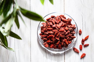  Beyaz ahşap bir masada cam bir tabakta kurumuş kurt üzümü. Organik, doğal, Çin kurt çileği kompozisyonu. Süperyiyecekler.