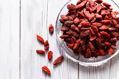  Beyaz ahşap bir masada cam bir tabakta kurumuş kurt üzümü. Organik, doğal, Çin kurt çileği kompozisyonu. Süperyiyecekler.