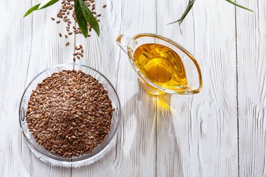 Keten tohumu yağı ve beyaz ahşap bir masada keten tohumu tohumu. Yağ ve keten tohumu, zeytin dalı ve uzayı kopyalayan modern natürmort..