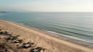 The drone flies going through the sand dunes towards the sea. Aerial Drone Footage high above the beach with the ocean.