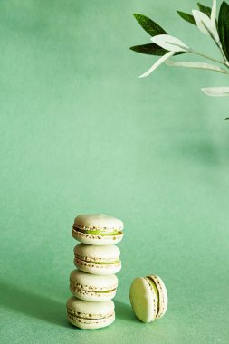 Açık yeşil arka planda, fotokopi alanı olan fıstıklı Fransız kurabiyeleri. Minimalist tatlı kompozisyonu.