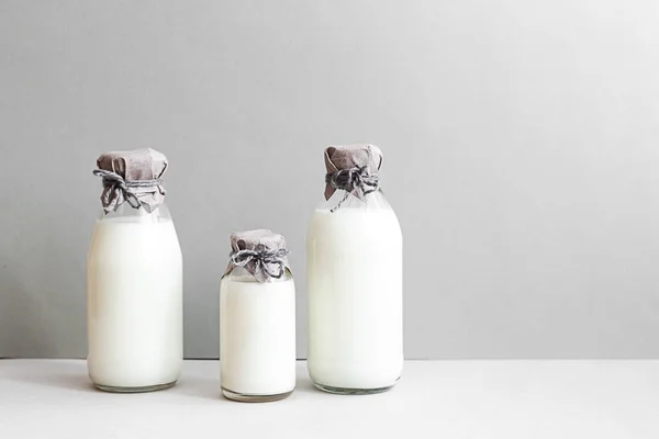 Minimal still life of milk bottles on a light background with copy space. Dairy production, organic product. The concept of healthy eating and sustainable lifestyle.