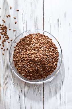 Beyaz ahşap masadaki cam kasede keten tohumları. Kapat ve boşluğu kopyala.