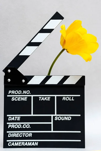 Clapboard from movie with yellow tulip. Minimal still life of clapper board for making video cinema and summer flowers.