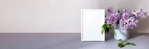 Minimalist iç mekândaki fotoğraf çerçevesini düzenle. Beyaz çerçeveli ve leylak buketli modern natürmort. Moda ev dekorasyonu kavramı. Pastel renklerde pankart.