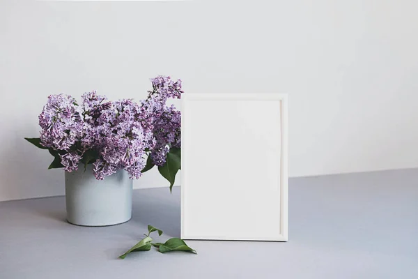 Minimalist iç mekândaki fotoğraf çerçevesini düzenle. Beyaz çerçeveli ve leylak buketli modern natürmort. Moda ev dekorasyonu kavramı. Pastel renklerde pankart.