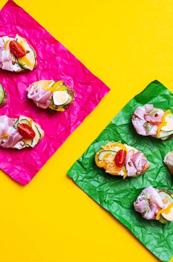 Bright summer still life of healthy, trendy snacks. Various sandwiches with cream cheese, quail eggs, tomatoes, bacon and vegetables. Flat lay in  minimalistic style.