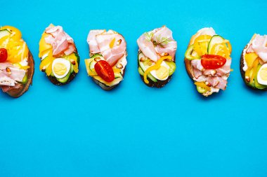 Trendy open sandwiches with cream cheese, quail eggs, tomatoes, bacon and vegetables. Modern, summer still life of healthy snacks.  Flat lay in minimalism style. Smorrebrod with various stuffing.