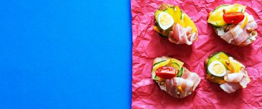 Çeşitli dolgulu açık sandviçler. Krem peynirli Smorrebrod, bıldırcın yumurtası, domates, pastırma ve sebze. Modern, yaz aylarında sağlıklı atıştırmalıklar. Minimalizm tarzında düz yatıyordu.