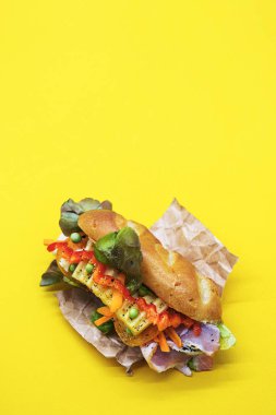 Banh mi vietnam sandviçi, çeşitli dolgulu, geleneksel kahvaltı. Sarı arkaplanda düz uzan, boşluğu kopyala.