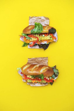 Banh mi vietnam sandviçi, çeşitli dolgulu, geleneksel kahvaltı. Sarı arkaplanda düz uzan, boşluğu kopyala.