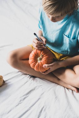 Sarışın çocuk evde Jack-o-Lantern yapıyor. Cadılar Bayramı konsepti.