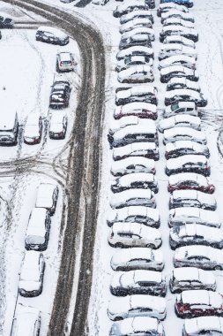 Otoparktaki ilk kar, yukarıdan görüş. Birçok araba karla kaplı..