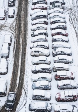 Otoparktaki ilk kar, yukarıdan görüş. Birçok araba karla kaplı..
