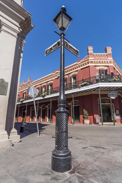 New Orleans, LA / USA - circa February 2016: Pole with street signs and old Colonial House with ironwork galleries on the Streets of French Quarter decorated for Mardi Gras in New Orleans, Louisiana — стоковое фото