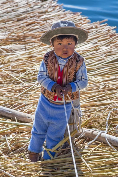 Puno, Perú - circa junio 2015: Niño pequeño con ropa tradicional en la isla flotante de Uros y pueblo en el lago Titicaca cerca de Puno, Perú — Foto de Stock