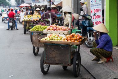 HO CHI MINH, VIETNAM - CIRCA AUGUST 2015: Vietnamese woman in traditional hat sells fruits in Ho Chi Minh City, Saigon,  Vietnam