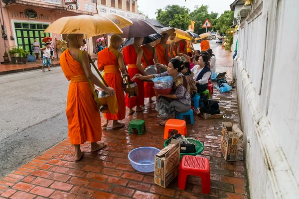 Luang Prabang, Laos - omstreeks augustus 2015: traditionele aalmoes geven ceremonie van de distributie van voedsel aan de boeddhistische monniken op de straten van Luang Prabang, Laos — Stockfoto