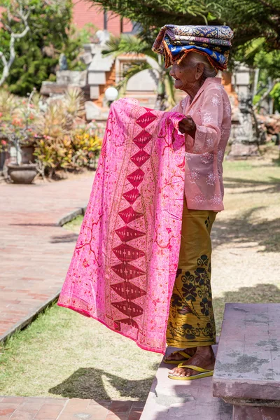 Semarapura, Bali/Indonesia - circa October 2015: Old woman sells sarong wraps in Klungkung Palace,   Semarapura — Stockfoto