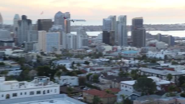 San diego, ca / usa - ca. januar 2016: flugzeug landet auf flughafen mit san diego city im hintergrund — Stockvideo