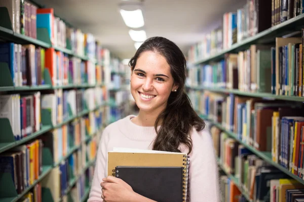 В библиотеке - симпатичная студентка с книгами, работающая в час — стоковое фото