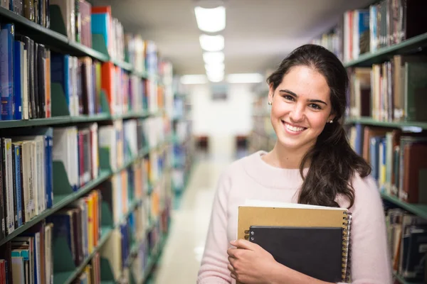 Dans la bibliothèque - jolie étudiante avec des livres qui travaillent en une heure — Photo