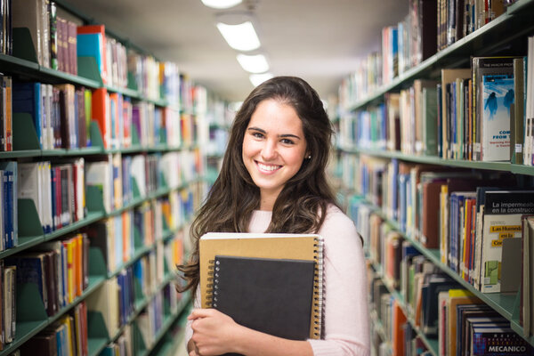 In the library - pretty female student with books working in a h