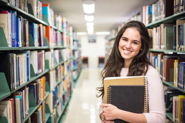 Dans la bibliothèque - jolie étudiante avec des livres qui travaillent en une heure — Photo