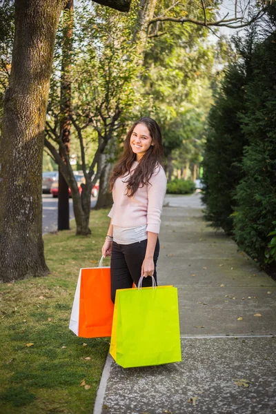 Compras chica joven sosteniendo bolsas de compras mirando a la cámara — Foto de Stock