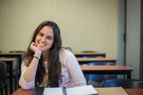 En el aula - estudiante bastante femenina con libros que trabajan en un —  Fotos de Stock