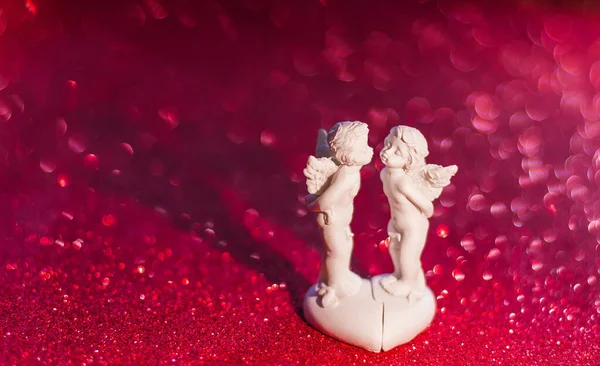 Two kissing angels on red background with bokeh Valentine\'s day Cupid, soft focus copy space