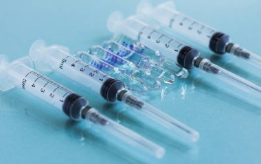 İğne için ampuller ve mavi arka planda şırıngalar. Aşı konsepti, aşılama ve aşılama mevsimi