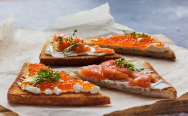 Sandviç ya da tapas ekmeği kırmızı havyar ve kırmızı balık mikro yeşillikler, deniz ürünleri lezzetli yiyecekler.  