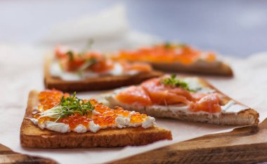 Sandviç ya da tapas ekmeği kırmızı havyar ve kırmızı balık mikro yeşillikler, deniz ürünleri lezzetli yiyecekler.   