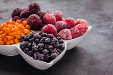 Donmuş meyveleri ve meyveleri siyah bir masaya yakın. Sağlıklı yiyecek vitaminleri, atıştırmalık tatlı.