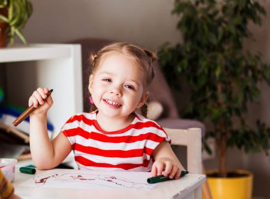 Küçük gülümseyen kız çocuklar masaya oturur ve keçeli kalemlerle resim çizer, mutlu bir çocukluk.