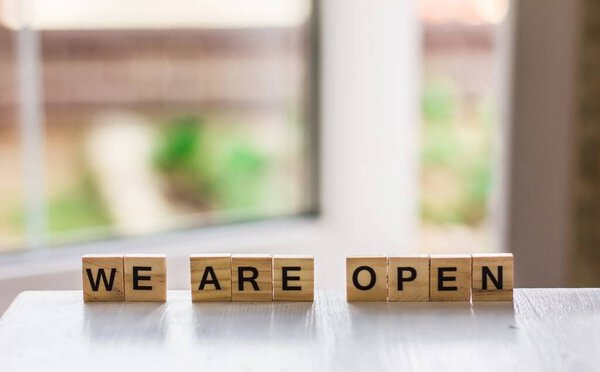 The word "we are open" made of wooden cubes on the background of an open door, End of quarantine  a cafe, a local shop, in welcoming guests after the coronavirus outbreak and the shutdown of people