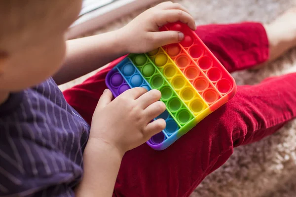 Modern renkli ve parlak popit oyuncağı basit gamzeli küçük sarışın çocuk portresi. Renkli anti-stres silikon duyusal oyuncağı olan çocuk.