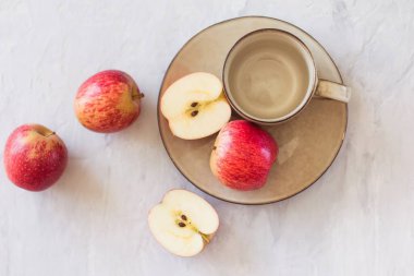 Gri arkaplanlı elmalar ve fincanlar. Sağlıklı beslenme ve vitamin kavramı. Fotokopi alanı olan düz bir yer. Yatay yönelim