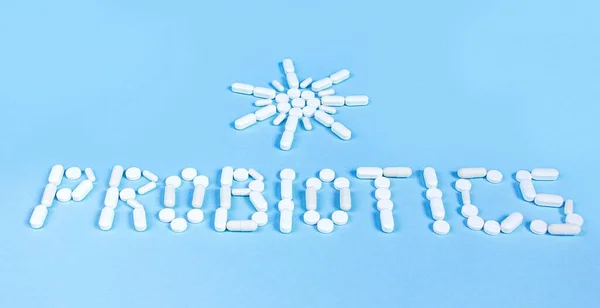 A palavra probióticos e o sol é colocado fora de comprimidos brancos em um fundo azul — Fotografia de Stock
