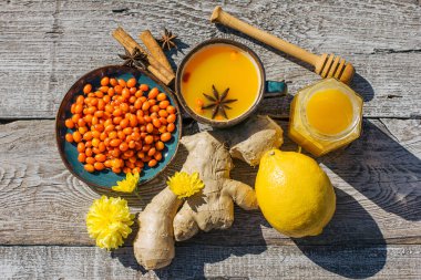 Tahta bir masada deniz dikenli çay, bal, limon ve zencefil. Soğuk çay sağlık, grip mevsimi ve üst görünüm için bir antioksidandır.