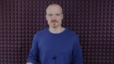 Mavi ceketli erkek hoparlör kameraya konuşuyor.