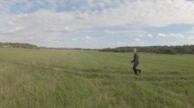 Bir adam kırsal alanda yürüyüş direkleri ile koşuyor.