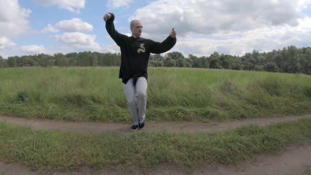 Wushu in der Natur, ein junger Mann macht Morgengymnastik — Stockvideo
